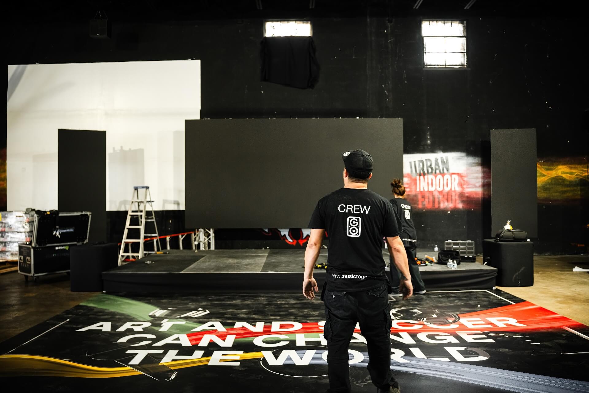 Indoor Stage LED Video Wall Event Production Setup Event production crew member looking at a newly assembled indoor LED video wall screen on a stage, perfect for professional corporate presentations, DJ concerts, and audio visuals.